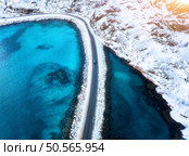 Aerial view of curved snowy road to the island and blue sea at sunset. Highway in snow and azure transparent water. Winter landscape. Top drone view of road in Lofoten islands, Norway. Travel. Стоковое фото, агентство Ingram Publishing / Фотобанк Лори