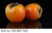 Red ripe persimmons rotating over black background. Стоковое фото, агентство Ingram Publishing / Фотобанк Лори