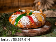 A festive King Cake adorned with colorful candied fruits, dusted with powdered sugar, and ready to be shared. Стоковое фото, агентство Ingram Publishing / Фотобанк Лори