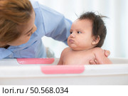A mother bathes her little daughter in a small children’s tub. Стоковое фото, агентство Ingram Publishing / Фотобанк Лори