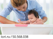 A mother bathes her little daughter in a small children’s tub. Стоковое фото, агентство Ingram Publishing / Фотобанк Лори