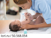 Following a bath, a mother applies powder and dresses her tiny daughter. Стоковое фото, агентство Ingram Publishing / Фотобанк Лори