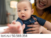 A tiny child cheerfully plays with toys on the floor of the living room with mom. Стоковое фото, агентство Ingram Publishing / Фотобанк Лори