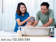 Parents bathe little child after ate meal. Стоковое фото, агентство Ingram Publishing / Фотобанк Лори