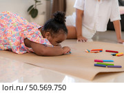 On a holiday, A woman and her little daughters sit on the floor and drawing together in the living room. Стоковое фото, агентство Ingram Publishing / Фотобанк Лори