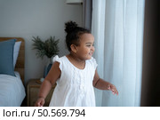 A tiny girl plays hide-and-seek with drapes in her bedroom. Стоковое фото, агентство Ingram Publishing / Фотобанк Лори