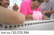 Three siblings save money by putting it in a piggy bank, This is an activity that parents teach their children about saving money. Стоковое фото, агентство Ingram Publishing / Фотобанк Лори