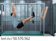 A young man doing pilates exercises on a pilates cadillac. Стоковое фото, агентство Ingram Publishing / Фотобанк Лори