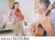 A girl violinist and her grandfather practice music together at home. Стоковое фото, агентство Ingram Publishing / Фотобанк Лори