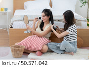 Asian young women conducting their weekly holiday routines from getting up, putting on cosmetics and relaxing. Стоковое фото, агентство Ingram Publishing / Фотобанк Лори