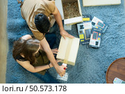High angle view of young couple packing boxes after selling things online via social media channels. Стоковое фото, агентство Ingram Publishing / Фотобанк Лори