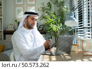 Portrait of young Arabic businessman working on laptop at home. Стоковое фото, агентство Ingram Publishing / Фотобанк Лори