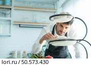 A young man puts on an apron to make dessert to eat with his wife. Checking the completeness of the finished dessert. Стоковое фото, агентство Ingram Publishing / Фотобанк Лори