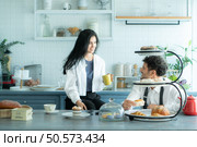 A husband wears an apron while cooking dinner with his wife. The duo took a break to sip coffee and sample the completed bread. Стоковое фото, агентство Ingram Publishing / Фотобанк Лори