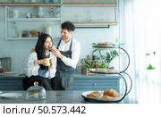 A husband wears an apron while cooking dinner with his wife. The duo took a break to sip coffee and sample the completed bread. Стоковое фото, агентство Ingram Publishing / Фотобанк Лори