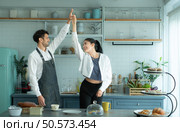 A husband wears an apron while cooking dinner with his wife. He was dancing happily before entering the kitchen to cook. Стоковое фото, агентство Ingram Publishing / Фотобанк Лори