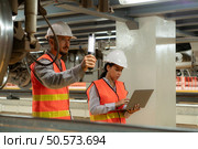 Male and female engineers work together in an electric repair station. Inspecting the undercarriage of electric train that are being repaired at the garage. Стоковое фото, агентство Ingram Publishing / Фотобанк Лори