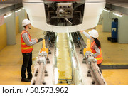 Male and female engineers work together in an electric repair station. Inspect head of electric trains that come in for repairs in the skytrain repair station. Стоковое фото, агентство Ingram Publishing / Фотобанк Лори
