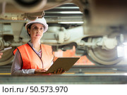 Male and female engineers work together in an electric repair station. Inspecting the undercarriage of electric train that are being repaired at the garage. Стоковое фото, агентство Ingram Publishing / Фотобанк Лори