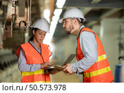 Male and female engineers work together in an electric repair station. Inspecting the undercarriage of electric train that are being repaired at the garage. Стоковое фото, агентство Ingram Publishing / Фотобанк Лори