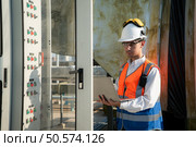 Before proceeding with the testing, Electrical engineer inspects the installed control panel. Стоковое фото, агентство Ingram Publishing / Фотобанк Лори