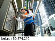 Before proceeding with the testing, Electrical engineer inspects the installed control panel. Стоковое фото, агентство Ingram Publishing / Фотобанк Лори