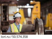 Railway technician in uniform and helmet inspect the train wheels removed from the locomotives in the train workshop. Стоковое фото, агентство Ingram Publishing / Фотобанк Лори