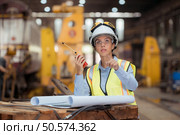 Portrait of railway technician worker in safety vest and helmet working with blueprint at train repair station. Стоковое фото, агентство Ingram Publishing / Фотобанк Лори
