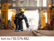 Railway technician in uniform and helmet inspect the train wheels removed from the locomotives in the train workshop. Стоковое фото, агентство Ingram Publishing / Фотобанк Лори
