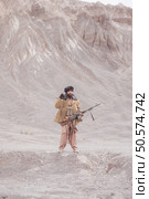 A Taliban soldier stands with a machine gun, In the desert mountain landscape. Стоковое фото, агентство Ingram Publishing / Фотобанк Лори