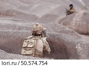 A Taliban soldier stands with a machine gun, Surrender to the allied soldiers, In the desert mountain terrain battlefield. Стоковое фото, агентство Ingram Publishing / Фотобанк Лори