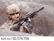 A Taliban soldier stands with a machine gun, Surrender to the allied soldiers, In the desert mountain terrain battlefield. Стоковое фото, агентство Ingram Publishing / Фотобанк Лори
