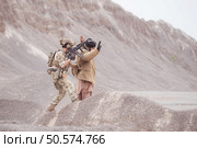 A Taliban soldier stands with a machine gun, Raise hands in surrender to the allied soldiers, In the desert mountain terrain battlefield. Стоковое фото, агентство Ingram Publishing / Фотобанк Лори