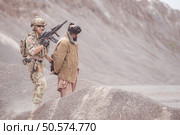 A Taliban soldier stands with a machine gun, Raise hands in surrender to the allied soldiers, In the desert mountain terrain battlefield. Стоковое фото, агентство Ingram Publishing / Фотобанк Лори