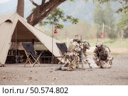 Group of soldiers in camouflage uniforms hold weapons in front of camp tent, Plan and prepare for combat training. Стоковое фото, агентство Ingram Publishing / Фотобанк Лори