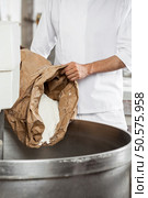 Midsection Of Mature Baker Pouring Flour In Kneading Machine. Стоковое фото, агентство Ingram Publishing / Фотобанк Лори