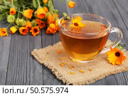 Calendula tea with fresh flowers on black wooden background. Стоковое фото, агентство Ingram Publishing / Фотобанк Лори