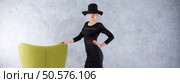 Woman in black dress, with black hat eclipsing her eyes and a hand based on green armchair. Стоковое фото, агентство Ingram Publishing / Фотобанк Лори