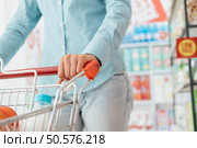 Woman doing grocery shopping at the supermarket, she is pushing a full shopping cart, hand close up, lifestyle and retail concept. Стоковое фото, агентство Ingram Publishing / Фотобанк Лори