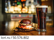 Hamburger and dark beer at the bar on wooden background. Hamburger and dark beer on a pub background. Стоковое фото, агентство Ingram Publishing / Фотобанк Лори
