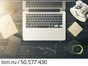 Top view of desktop with blank notepad, laptop, coffee, flowers and other items. Mock up. Стоковое фото, агентство Ingram Publishing / Фотобанк Лори