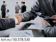 closeup of two businessmen shaking hands and the hands of the accountant counting on the tablet benefits from the transaction.photo on the background of the office.. handshake of business partners after discussion of the financial. Стоковое фото, агентство Ingram Publishing / Фотобанк Лори