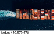 Aerial top view of cargo ship with contrail in the ocean sea ship carrying container and running for export cargo from container international yard port to custom ocean concept freight shipping by ship service. Стоковое фото, агентство Ingram Publishing / Фотобанк Лори