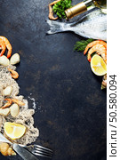 Delicious fresh fish and seafood on dark vintage background. Fish, clams and  shrimps with aromatic herbs, spices and vegetables - healthy food, diet or cooking concept. Стоковое фото, агентство Ingram Publishing / Фотобанк Лори