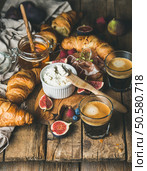 Breakfast with croissants, ricotta cheese, figs, fresh berries, prosciutto meat, honey in glass jar and two glasses of espresso coffee over rustic wooden background, selective focus. Breakfast with croissants, ricotta, figs, berries, prosciutto, honey and espresso. Стоковое фото, агентство Ingram Publishing / Фотобанк Лори