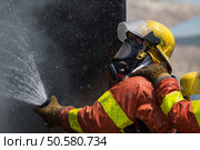 fireman in helmet and oxygen mask  spraying water to fire surround with smoke and drizzle. Стоковое фото, агентство Ingram Publishing / Фотобанк Лори