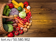 Fresh vegetables next to the overturned basket on the wooden surface. Стоковое фото, агентство Ingram Publishing / Фотобанк Лори