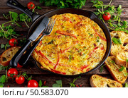 Frittata made of eggs, potato, bacon, paprika, parsley, green peas, onion in iron pan. on wooden table. Frittata made of eggs, potato, bacon, paprika, parsley, green peas, onion, cheese in iron pan. on wooden table. Стоковое фото, агентство Ingram Publishing / Фотобанк Лори