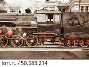 Retro steam train stands by the station building before departure.. Retro steam train. Стоковое фото, агентство Ingram Publishing / Фотобанк Лори