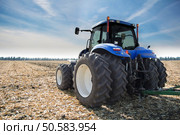 Blue tractor with a trailer on the field under blue sky. Стоковое фото, агентство Ingram Publishing / Фотобанк Лори